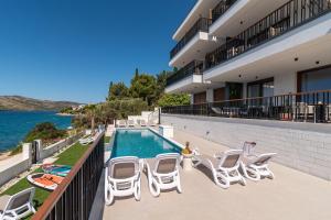 a balcony with chairs and a swimming pool at Royal Oak beachfront residence Trogir Seget Vranjica in Seget Vranjica