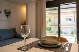 a table with a bowl and a wine glass on it at AKSQUARED Premium Vacation Apartments in Paralia Dionysiou