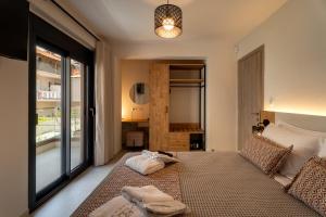a bedroom with a bed and a large window at AKSQUARED Premium Vacation Apartments in Paralia Dionysiou