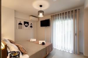 a bedroom with a bed and a large window at AKSQUARED Premium Vacation Apartments in Paralia Dionysiou