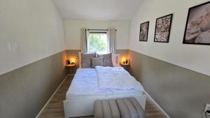 a small bedroom with a white bed with two lamps at Ferienhaus-Bambi in Haren