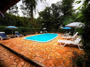 a swimming pool with two lawn chairs and umbrellas at Casa do Zeca Morretes in Morretes
