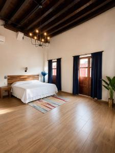 a bedroom with a white bed and a wooden floor at Palacio de las Rosas in Durango