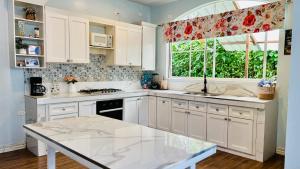 a kitchen with white cabinets and a large window at Hermosa casa con aire acondicionado rodeada de aves y naturaleza incluye desayuno in Puyo