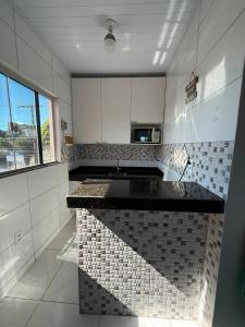 a kitchen with white cabinets and a black counter top at Apt Serras Gerais Superior in Dianópolis