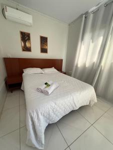a bedroom with a white bed with towels on it at Apt Serras Gerais Superior in Dianópolis
