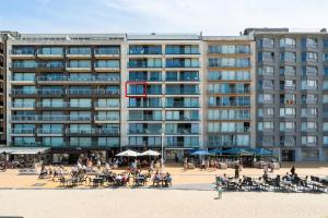 a large building with people sitting on the beach in front of it at Lombardie 0502 in Nieuwpoort