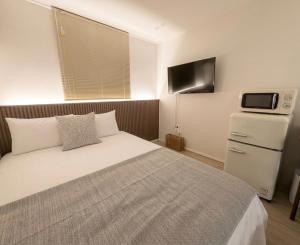 a bedroom with a bed and a tv on the wall at 303 Stayonyou Gocheok Dome Hongdae Subway 3Min in Gwangmyeong