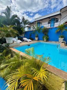 a swimming pool in front of a blue building with plants at Luah Buziana in Búzios +36 photos