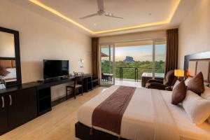 a hotel room with a bed and a large window at Cassandra Culture Resort in Sigiriya