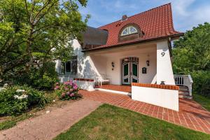 a small white house with a red roof at Villa-Magnolia-H in Hohwacht