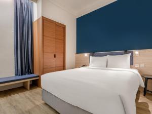 a bedroom with a large white bed and a blue wall at CHECK inn Select Taipei Nangang in Taipei +46 photos