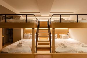 two bunk beds in a room with white sheets at SoMA Kagurazaka in Tokyo