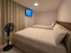 a bedroom with two beds and a flat screen tv at Hotel Balcones del Estadio in Medellín +73 photos