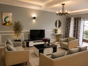a living room with couches and a flat screen tv at The Blue Resort in Yaoundé