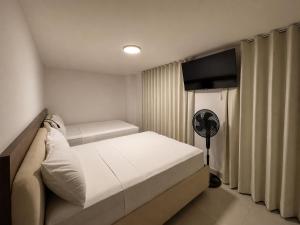a small bedroom with a bed and a fan at Hotel Balcones del Estadio in Medellín