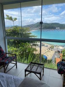 a room with a large window with a view of the ocean at Pousada Mirante do Atalaia Oficial II in Arraial do Cabo