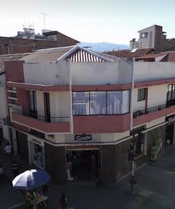 a red and white building with an umbrella on a street at Arbórea Casa Boutique in Cuenca