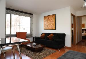 a living room with a black couch and a table at Hotel Suites 108 in Bogotá