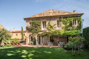 a large stone house with a green yard at L’Hort de Sant Cebrià in Torroella de Fluviá