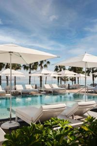 a swimming pool with white lounge chairs and umbrellas at W Barcelona in Barcelona