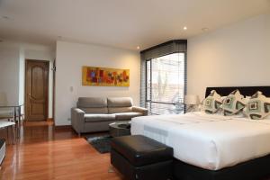 a bedroom with a large white bed and a couch at Hotel Suites 108 in Bogotá