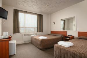 a hotel room with two beds and a television at Kiwi International Hotel in Auckland