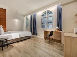 a bedroom with a bed and a desk and a window at CHECK inn Select Taipei Nangang in Taipei