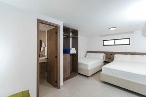 a white bedroom with two beds and a mirror at Hotel Balcones del Estadio in Medellín