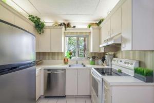 a kitchen with white cabinets and stainless steel appliances at Jupiter Bay Beach Condo in Jupiter +8 photos