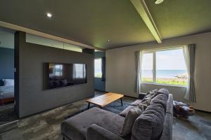 a living room with a couch and a tv at Aoyagi Stay in Shiomichō