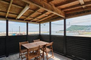 a table and chairs on a balcony with a view of the ocean at Aoyagi Stay in Shiomichō