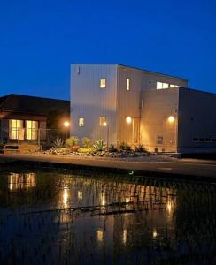 a building next to a body of water at night at sana plus in Asakura