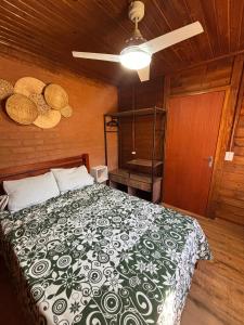 a bedroom with a bed with a black and white blanket at Recanto Sol Maior - Casa Lírio in Sapucaí-Mirim