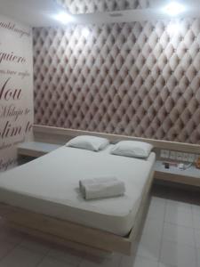 a white bed in a room with a wall at Eros Motel Hotel in Caicó