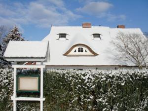 ein Haus mit einem schneebedeckten Dach auf einer Hecke in der Unterkunft Maisonette zum Weststrand in Prerow