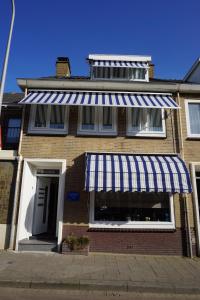 a brick house with a blue and white awning at Bed and Breakfast Kik en Bun in Katwijk aan Zee