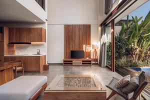 a living room with a bed and a tv and a couch at Teratai Villa Canggu by Ini Vie Hospitality in Canggu +25 photos