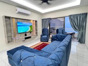 a living room with a blue couch and a tv at Tanjung Tuan Beach Regency - Hermis Theme 1 Car Park in Kampong Baharu