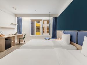 a hotel room with two beds and a desk at CHECK inn Select Taipei Nangang in Taipei