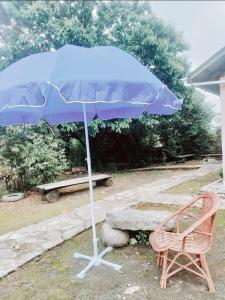 a blue umbrella next to a chair and a bench at Rimaaia farm house in Lāitlyngkot