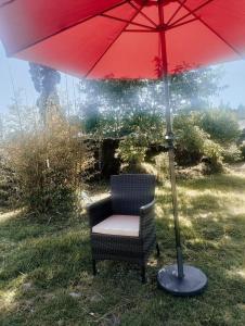 a chair under a red umbrella in the grass at Rimaaia farm house in Lāitlyngkot