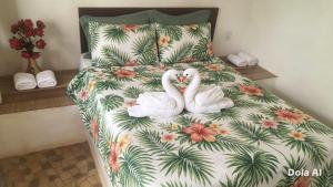 two swans sitting on a bed with a floral bedspread at Pousada Rainha das Águas in Ilhéus +88 photos