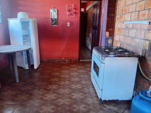 a kitchen with a stove and a red wall at Wana Soeiro in Marapanim +5 photos