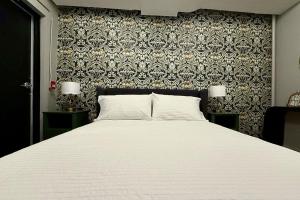 a bedroom with a large white bed with a wall at Danforth Hotel in Toronto +3 photos