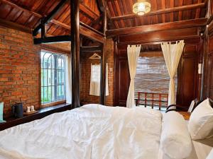 a bedroom with a white bed and a brick wall at La Belle Saison Homestay Huế in Hue
