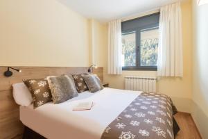 a bedroom with a large white bed with a window at Pierre & Vacances Andorra Sunari Peretol in Bordes d´Envalira