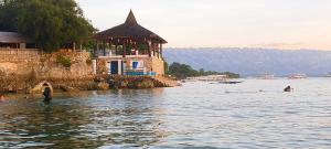 a person standing in the water next to a building at Love's Beach & Dive Resort in Moalboal