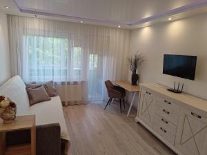 a living room with a couch and a tv on the wall at Mirdzas Ķempes iela 14 in Liepāja