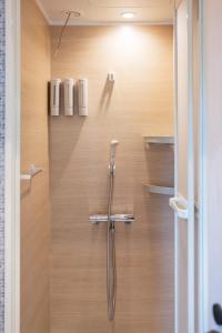 a shower in a bathroom with a wooden wall at guest house ALO in Miyako-jima